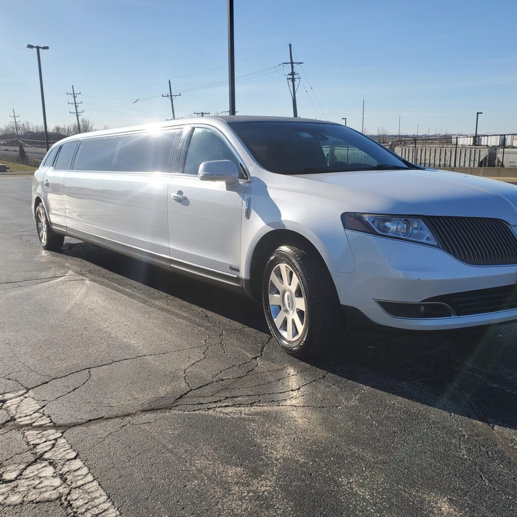 A white limousine is parked on a paved surface in an open area on a sunny day. The vehicle is elongated with tinted windows.